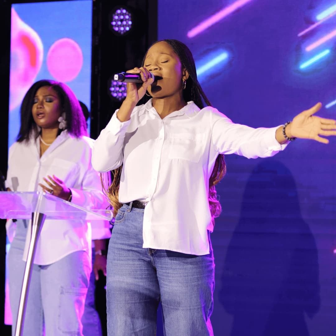 Two worship leaders singing on stage with arms outstretched